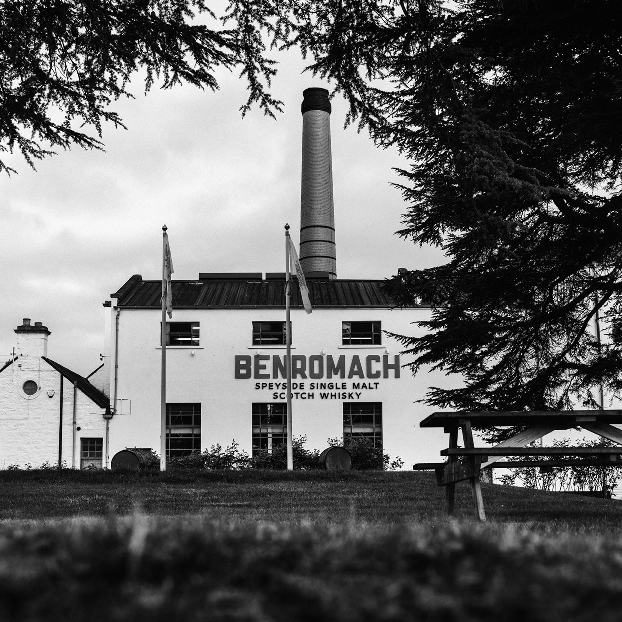 An image of Benromach Distillery taken from the outside with branding and flags visible
