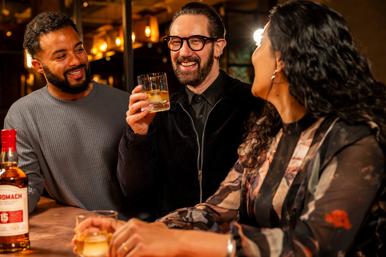 An image of three people in a bar drinking Benromach 15 year old single malt Scotch whisky.