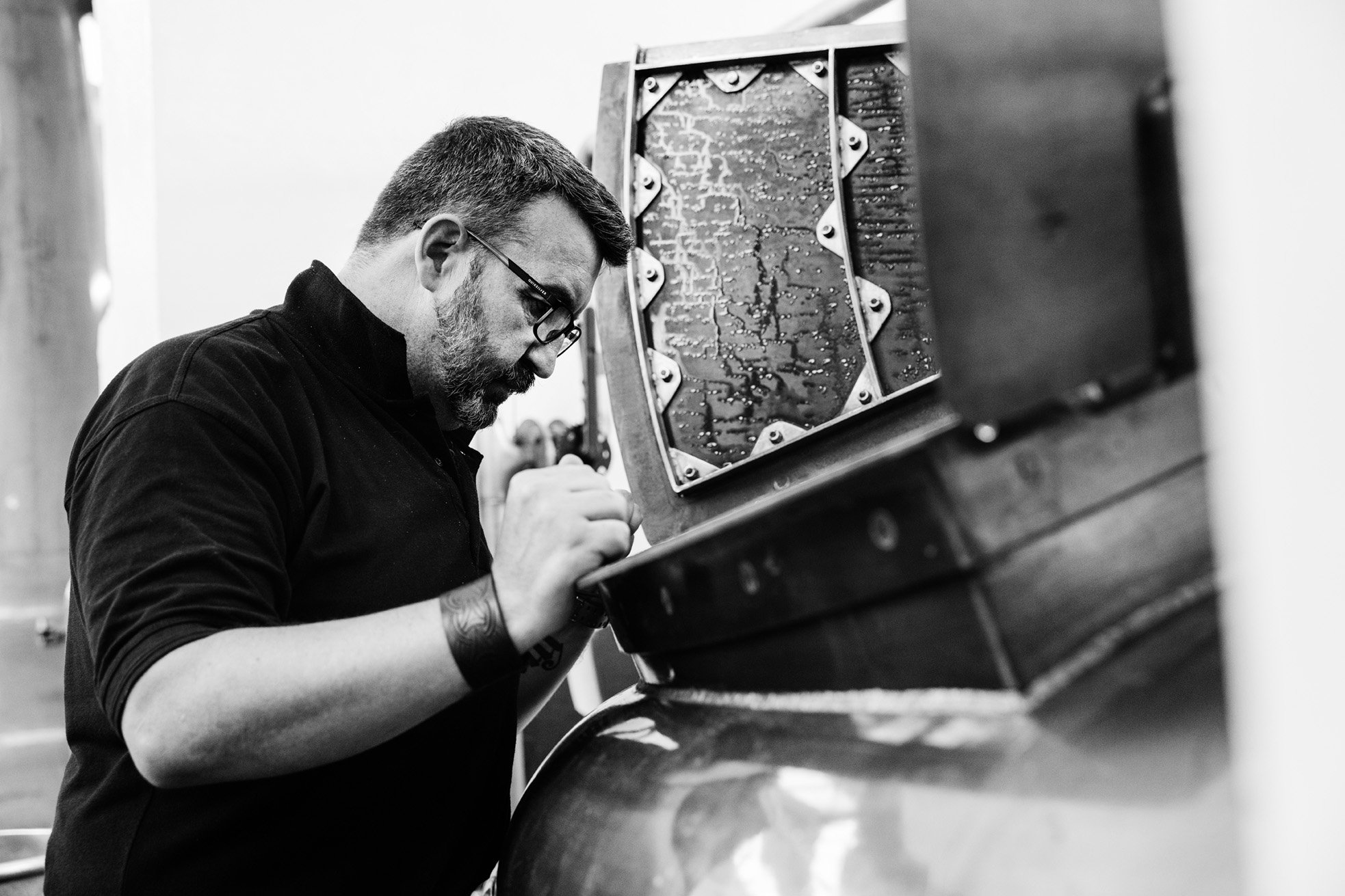 An image of a male distillery worker looking into Benromach Distillery mash tun An image of a male distillery worker looking into Benromach Distillery mash tun