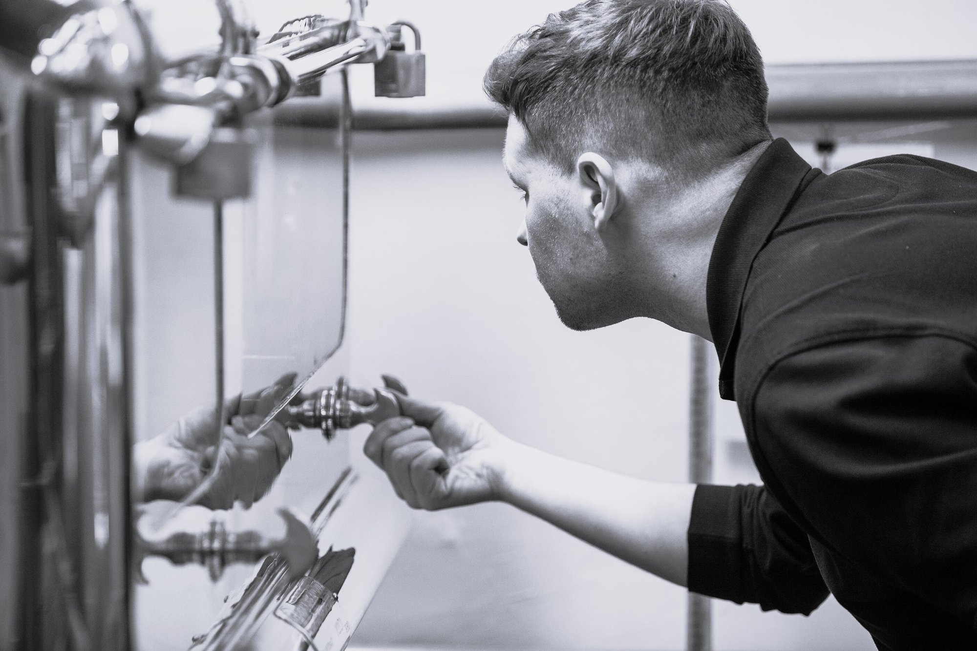 An image of our distiller checking the spirit safe to make Benromach Single Malt Scotch Whisky